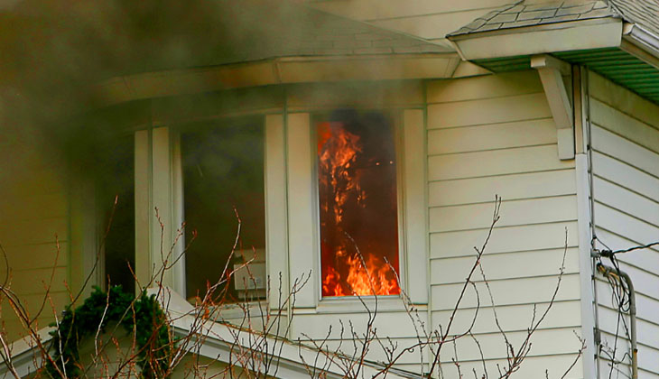 Smoke billowing out of a window with flames inside